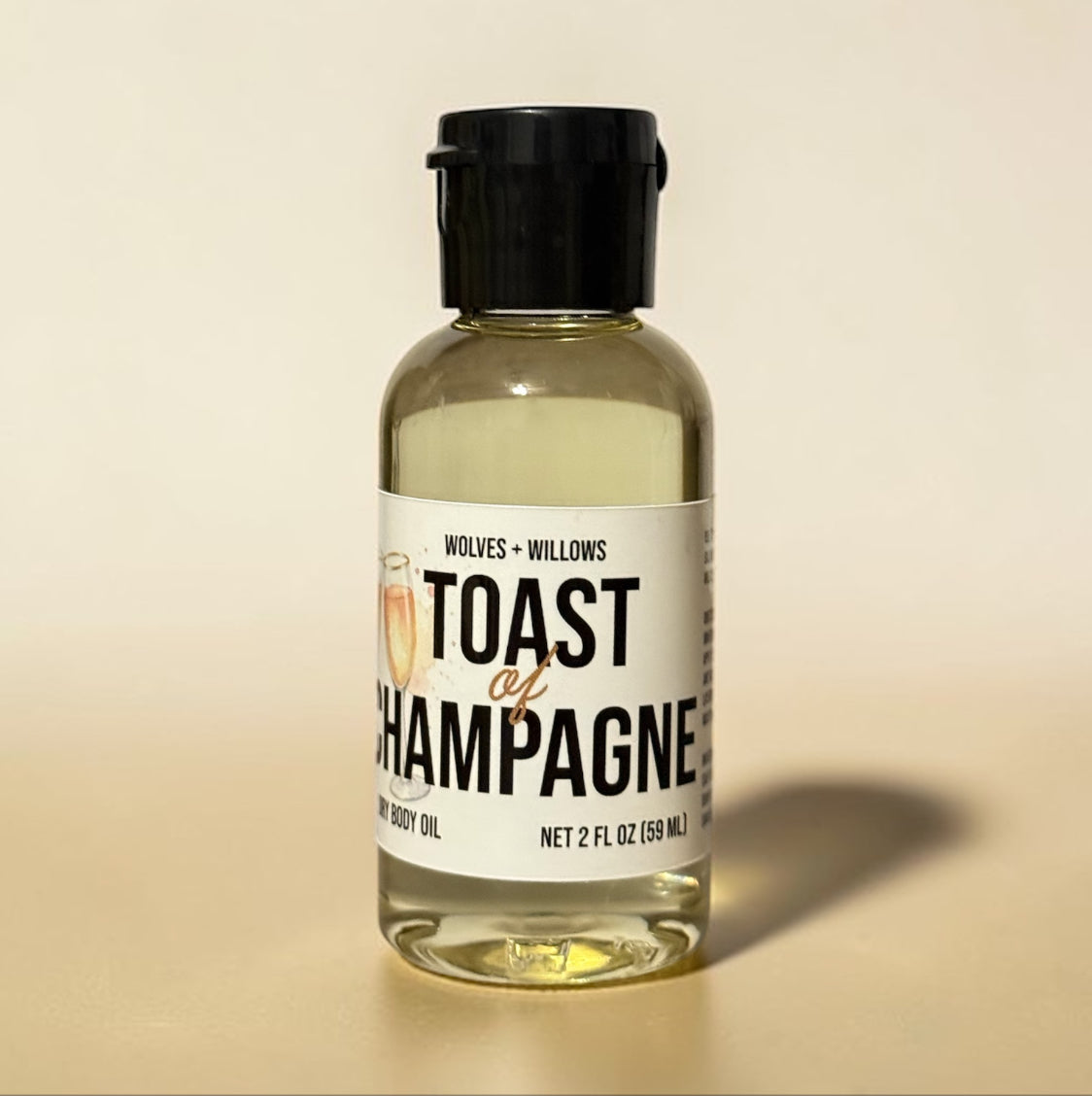 Bottle of 'Toast of Champagne' body oil by Wolves & Willows on a beige background