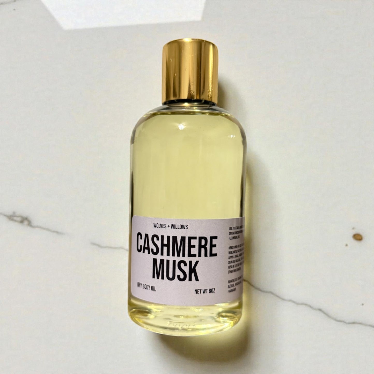 8 ounce 'Cashmere Musk' body oil in clear bottle with gold dispensing cap.