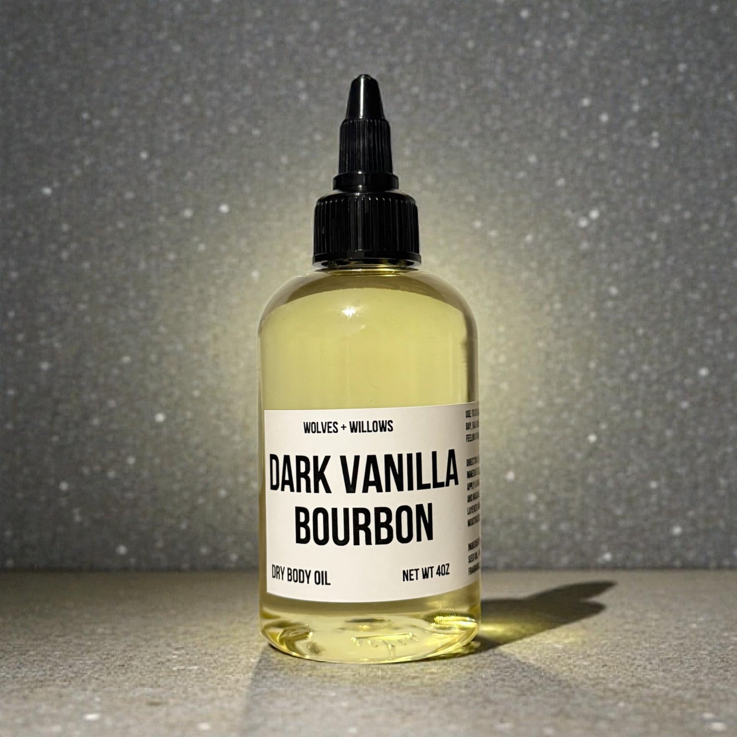 dark vanilla bourbon body oil in 4 ounce bottle with black twist dispensing cap.