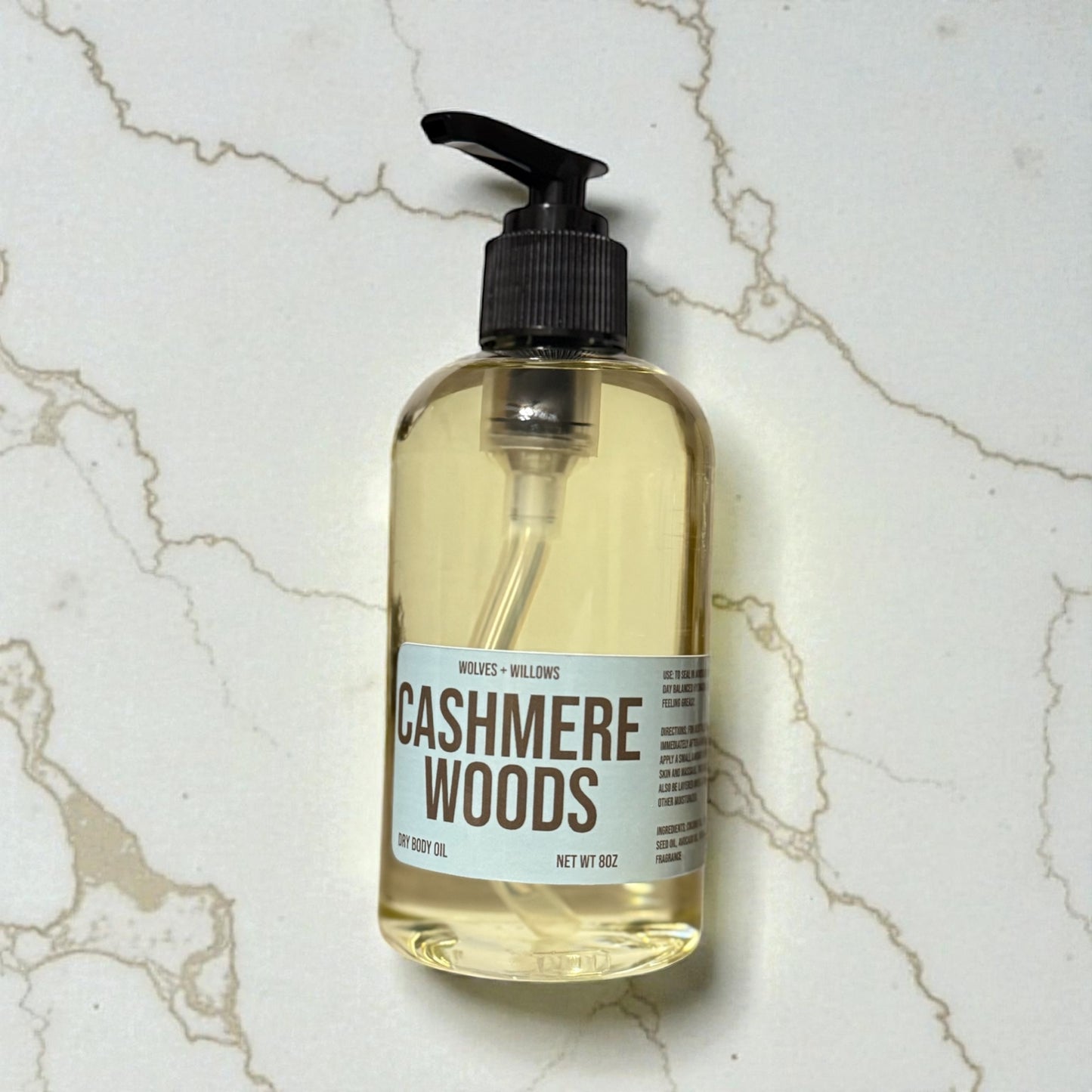 8 ounce 'Cashmere Woods' body oil in clear bottle with black pump.