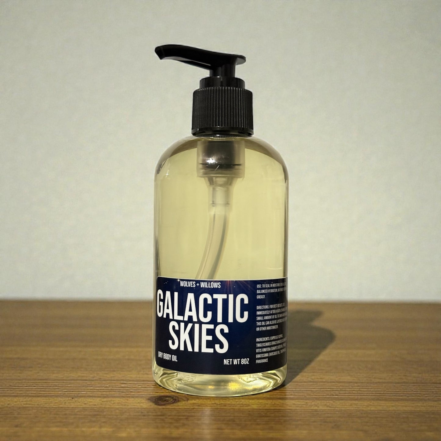 Bottle of 'Galactic Skies' body oil on a wooden surface with a neutral background