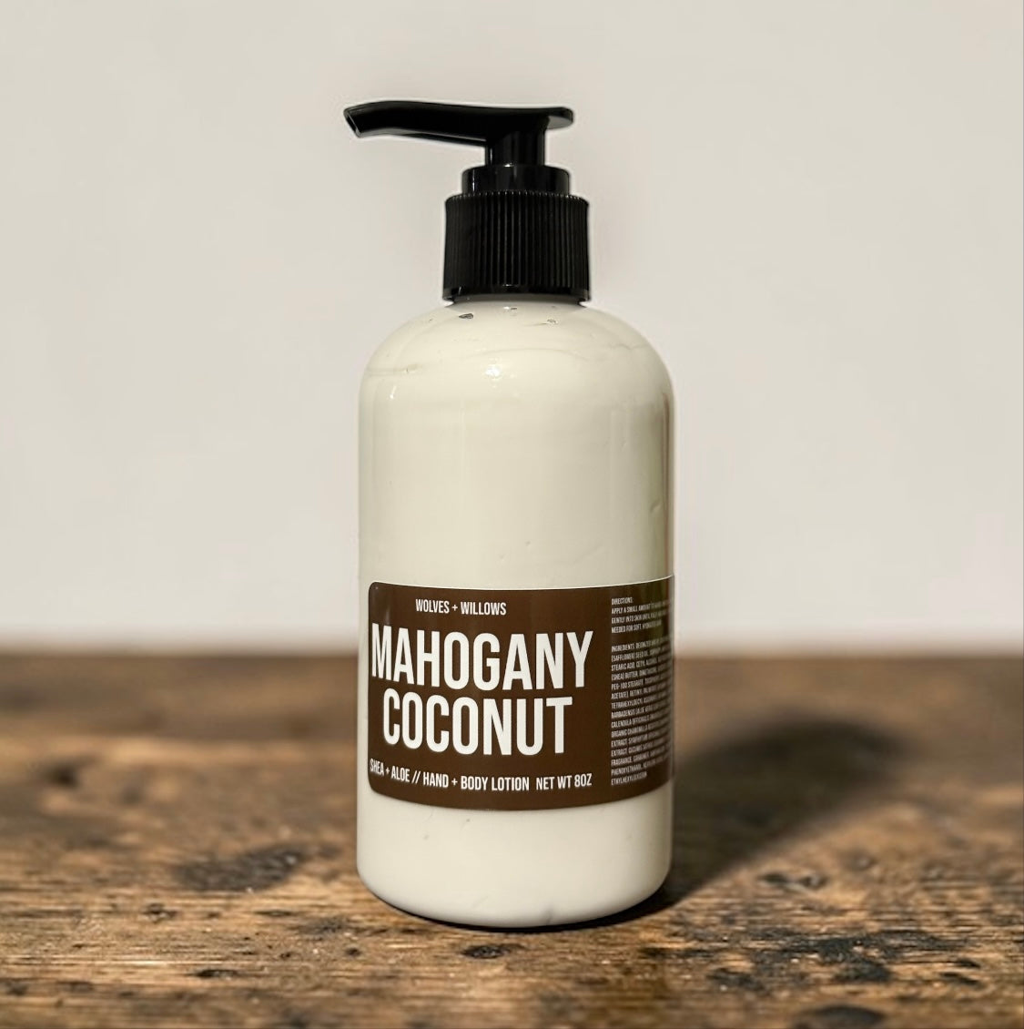 Lotion bottle labeled 'Mahogany Coconut' on a wooden surface with a neutral background