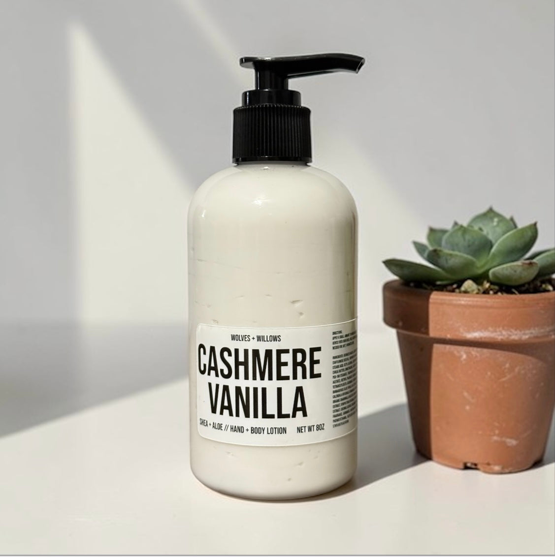 Body lotion bottle labeled 'Cashmere Vanilla' on a light surface with a plant in the background