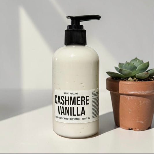 Body lotion bottle labeled 'Cashmere Vanilla' on a light surface with a plant in the background