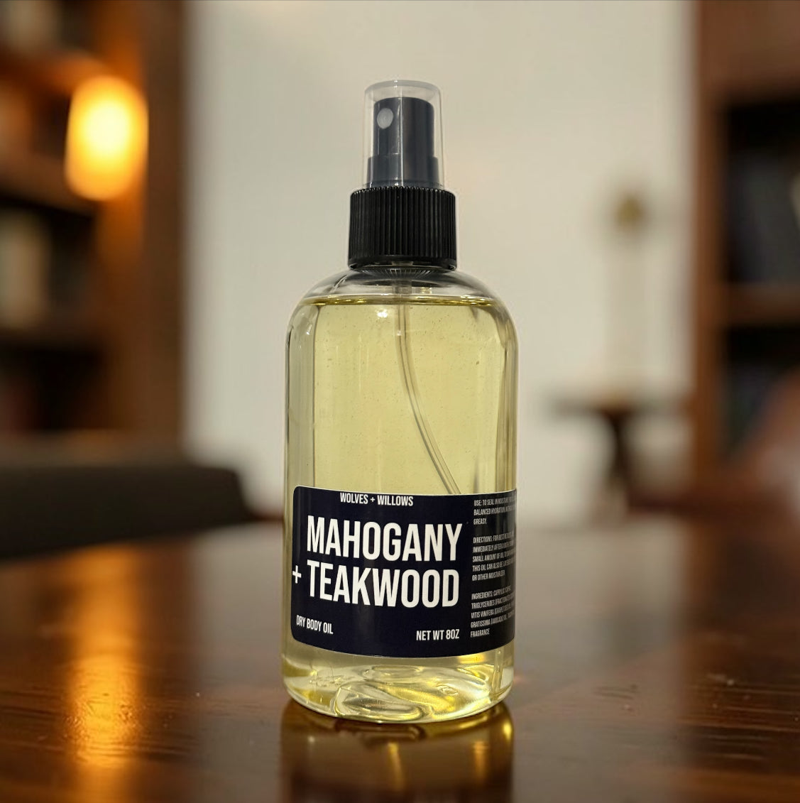 Bottle of Mahogany + Teakwood dry body oil on a wooden surface with a blurred background