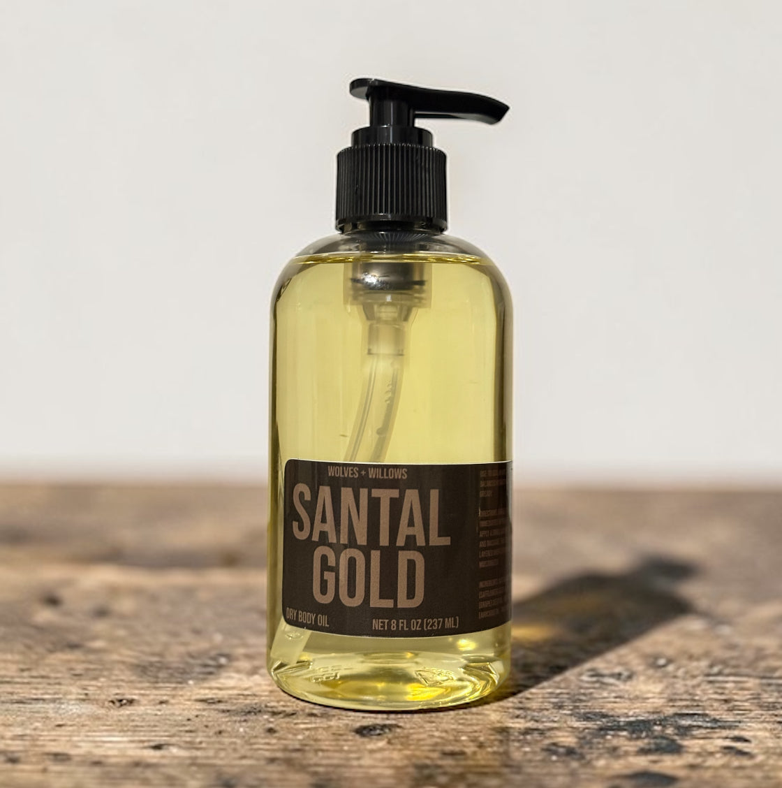 Bottle of Santal Gold body oil on a wooden surface with a neutral background