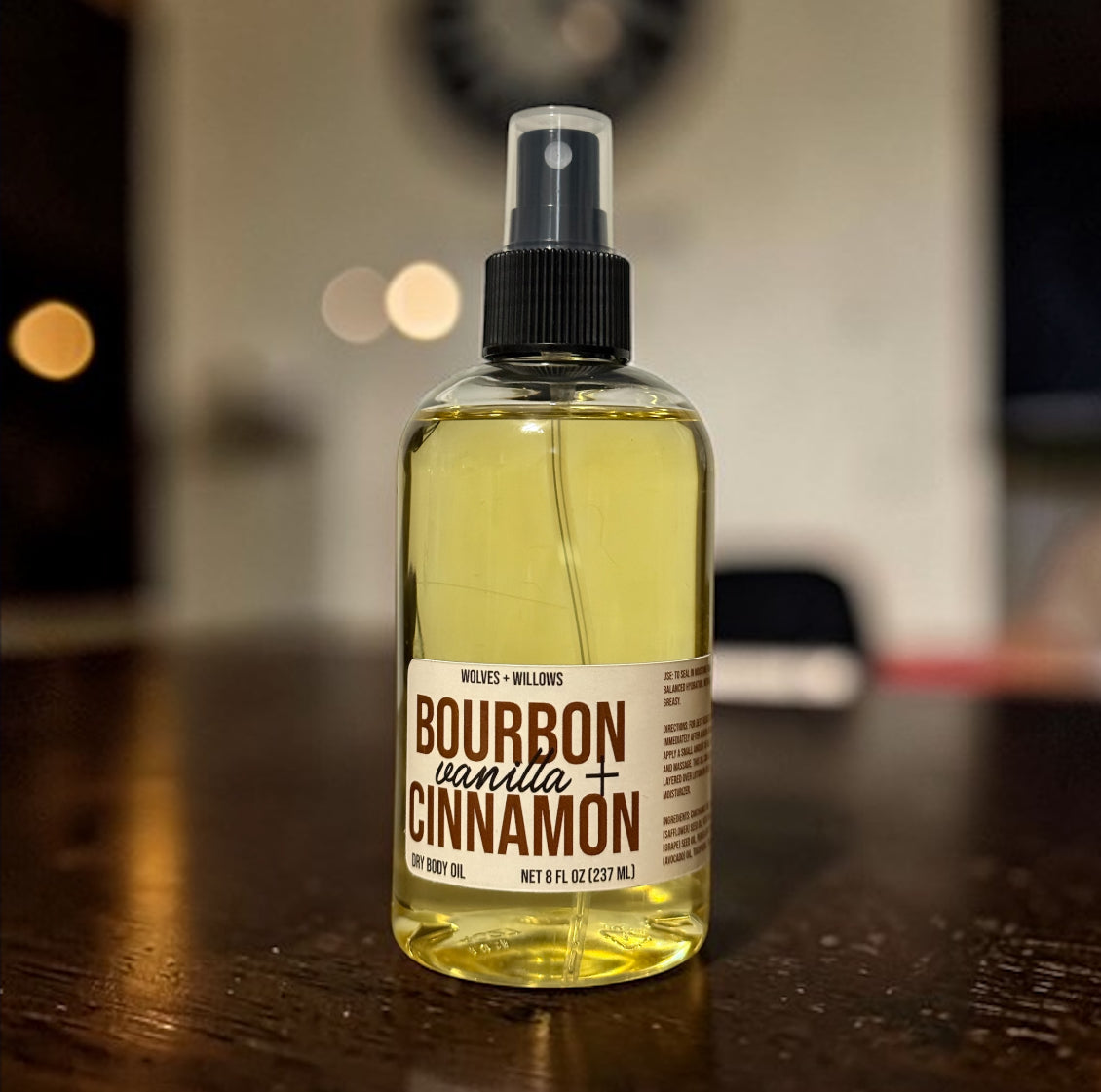 Bottle of bourbon vanilla cinnamon dry body oil on a wooden surface with a blurred background
