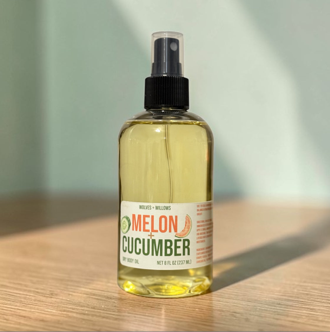 Bottle of melon cucumber body oil on a wooden surface with a blurred background