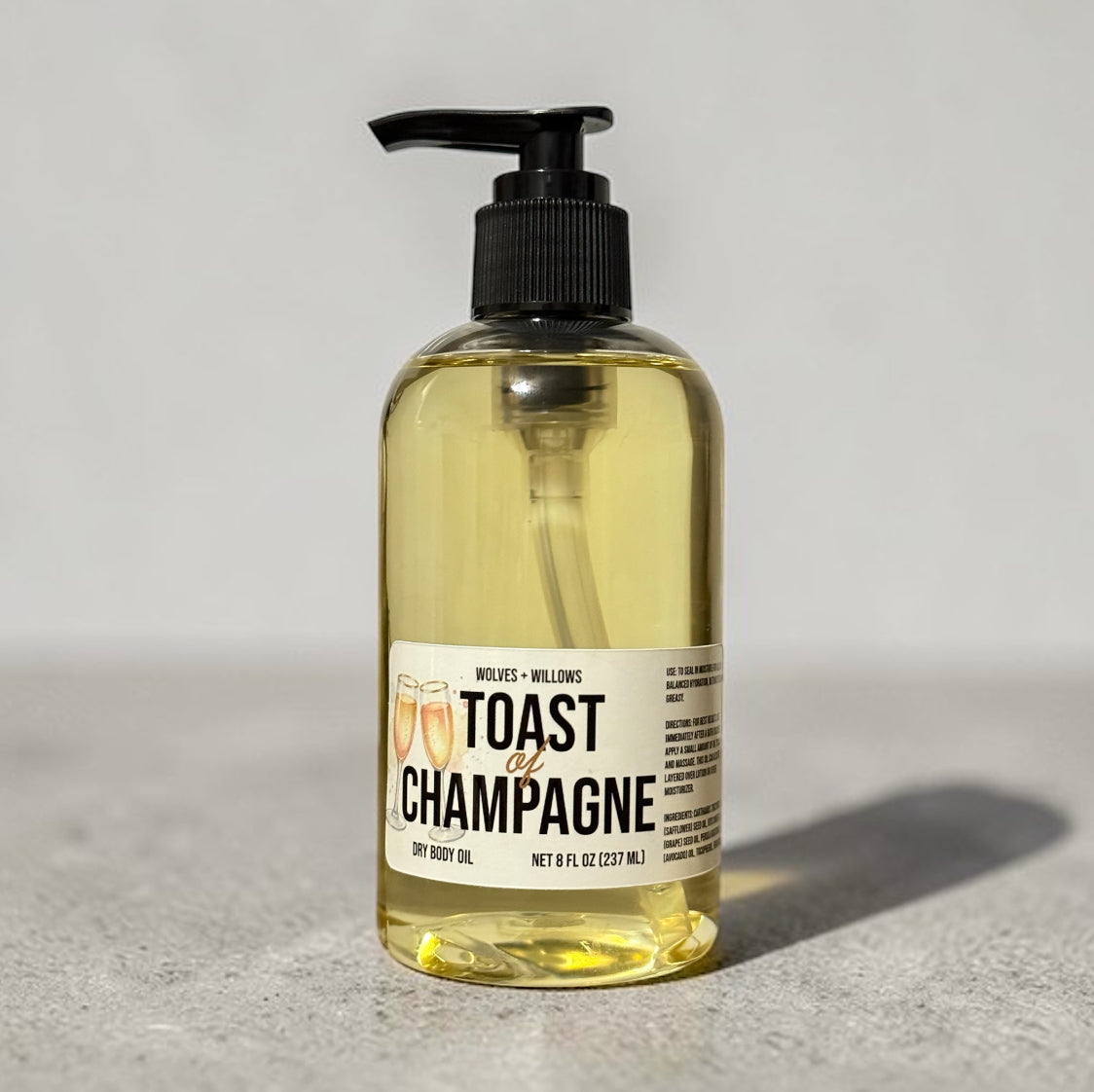 Bottle of 'Toast of Champagne' dry body oil on a gray background