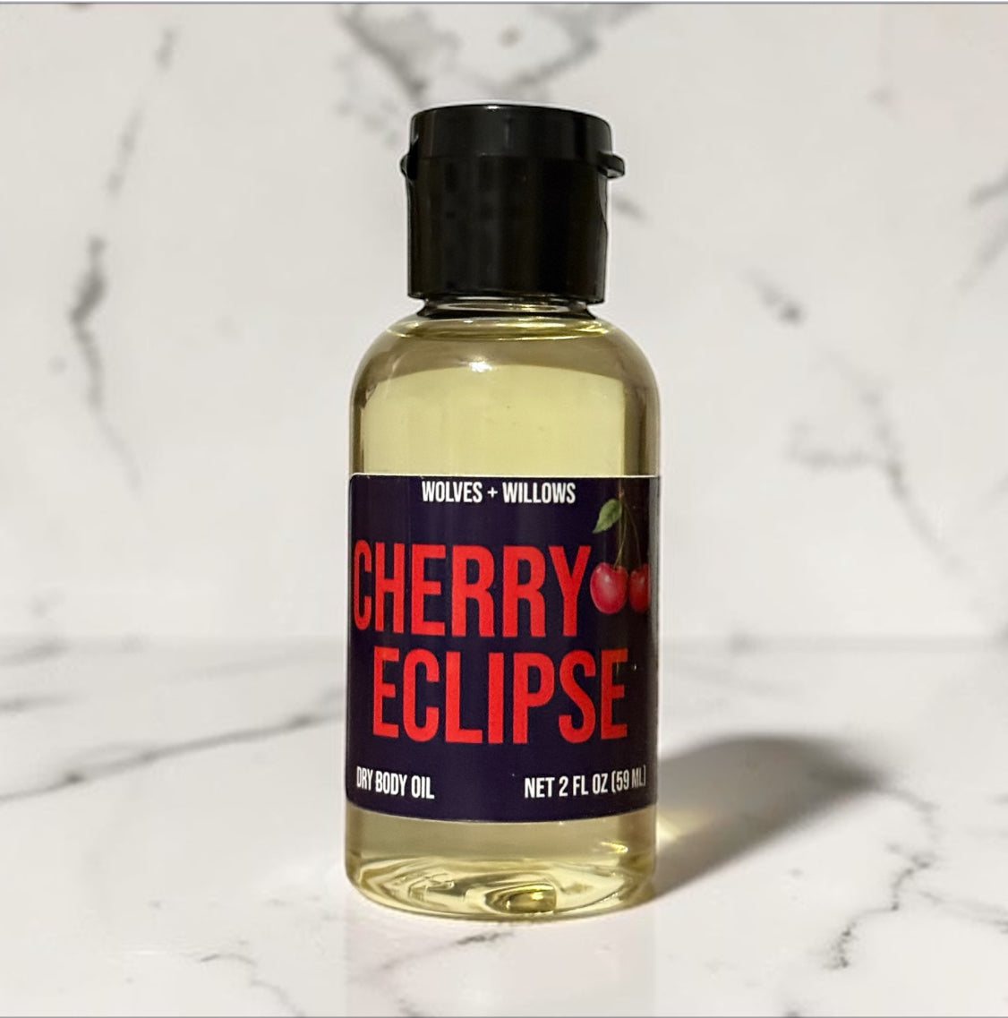 Bottle of Cherry Eclipse dry body oil on a marble surface