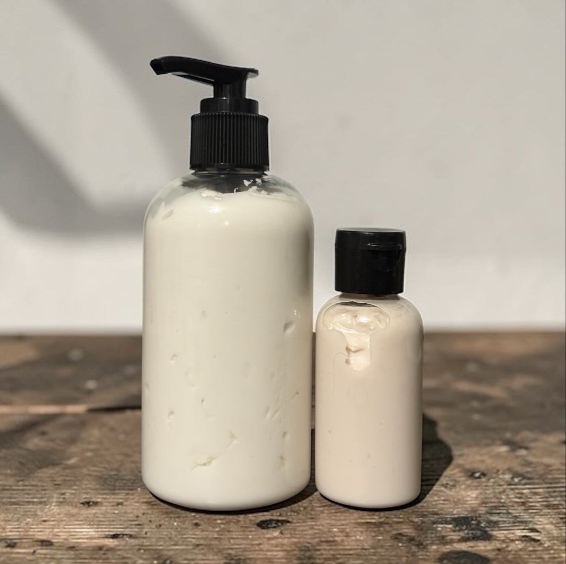 Two white bottles with black pump caps on a wooden surface.