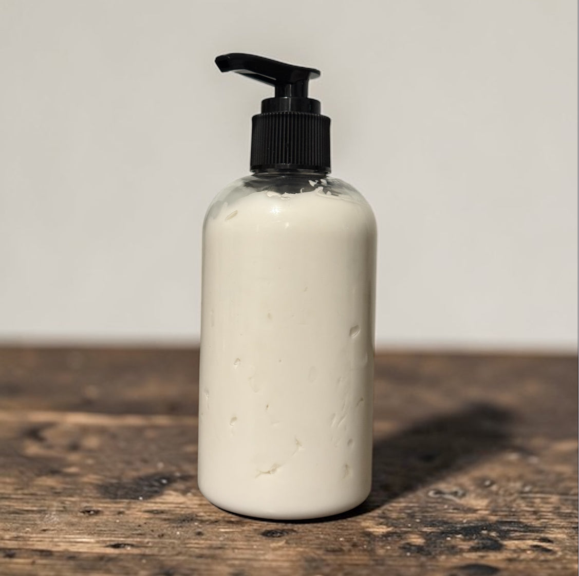 White bottle with black pump on a wooden surface