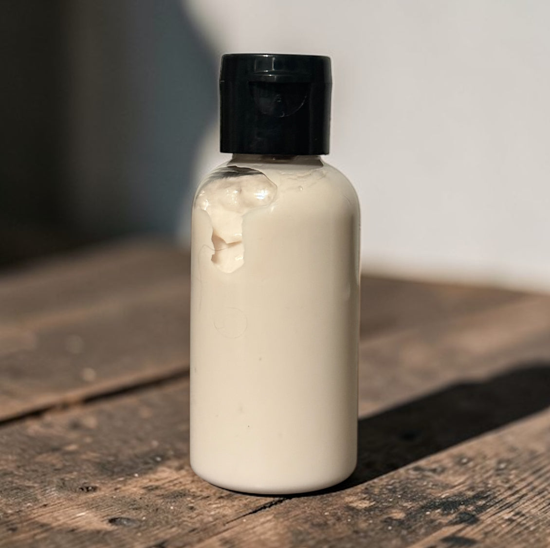 Small bottle with a black cap on a wooden surface