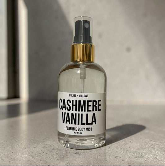 Clear spray bottle labeled 'Cashmere Vanilla' on a concrete surface with a neutral background