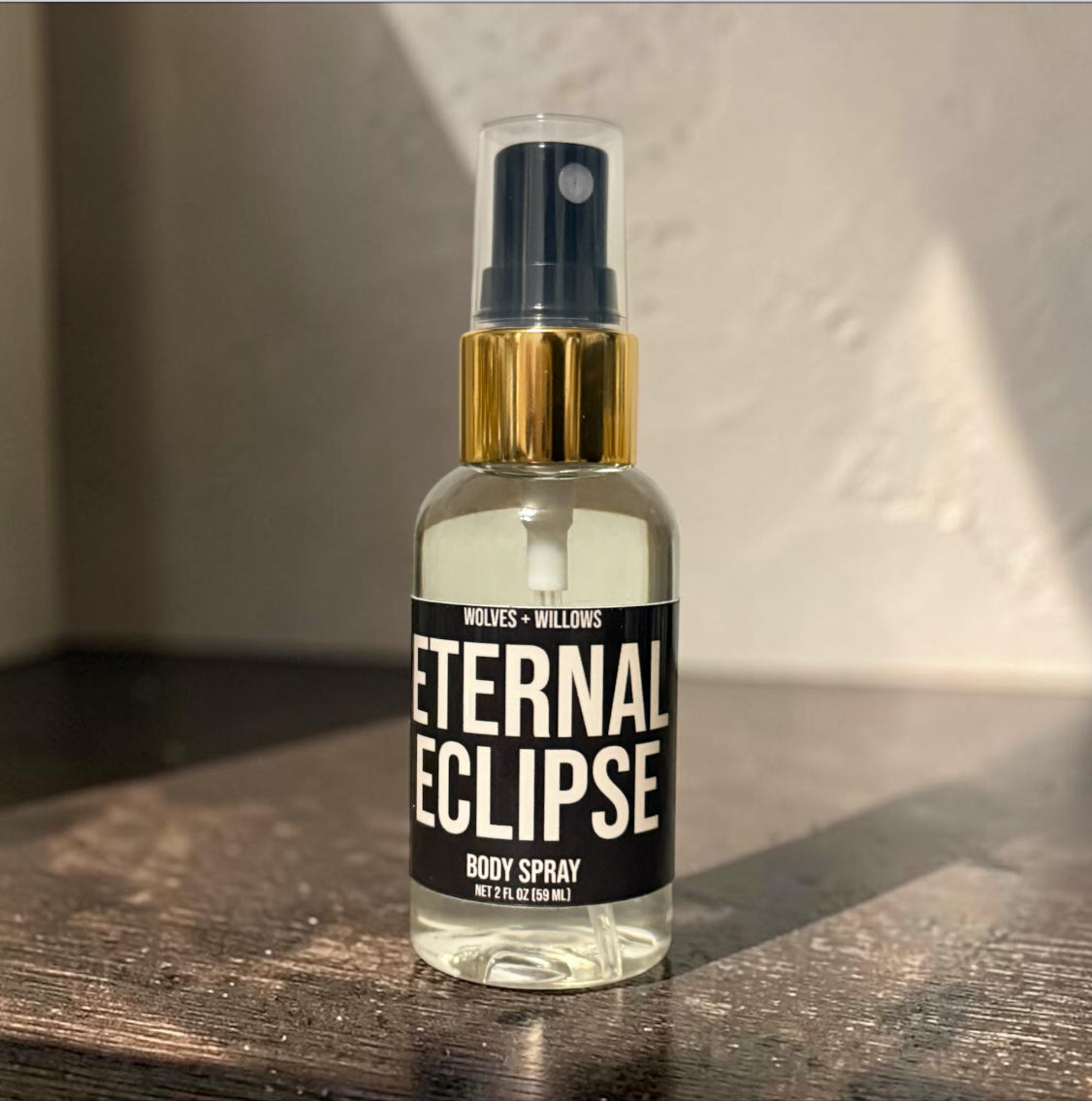 Body spray bottle labeled 'Eternal Eclipse' by Wolves & Willows on a wooden surface.