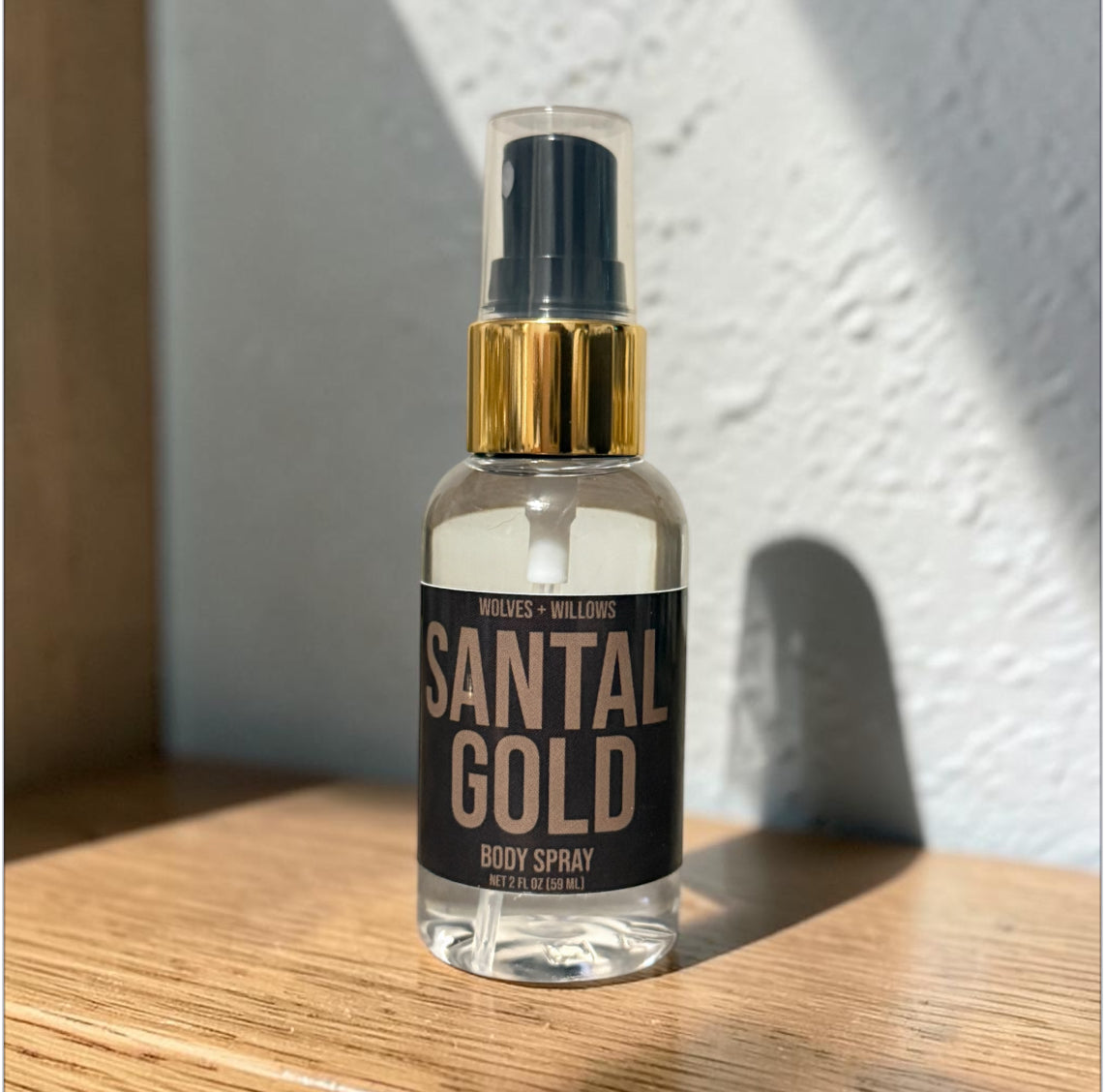 Santal Gold body spray bottle on a wooden surface with a light background