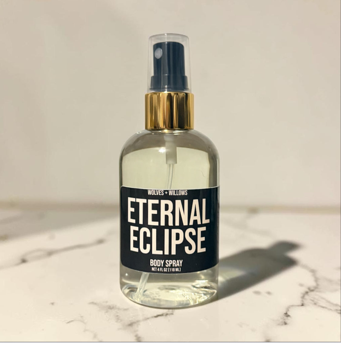 Body spray bottle labeled 'Eternal Eclipse' on a marble surface with a neutral background