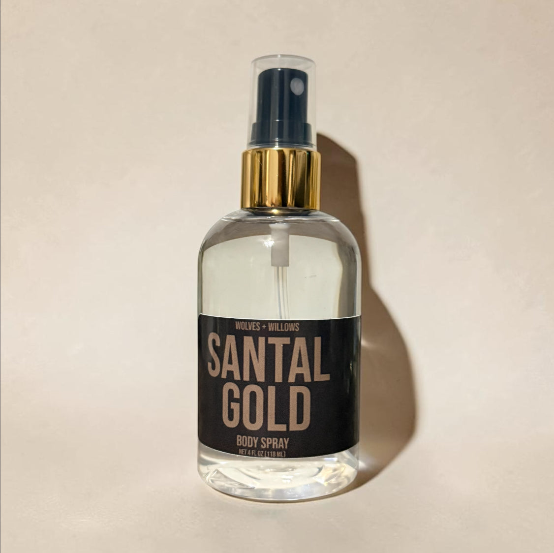 Clear spray bottle labeled 'Santal Gold' on a beige background
