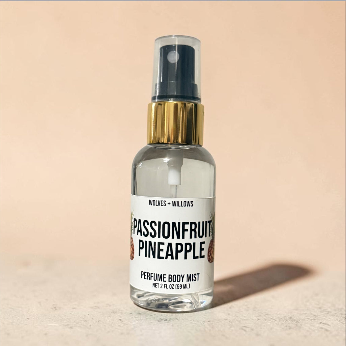 Passionfruit Pineapple perfume body mist bottle with gold cap on a beige background