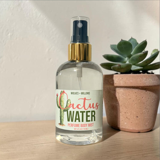 Bottle of 'Cactus Water' perfume body mist with a cactus plant in the background
