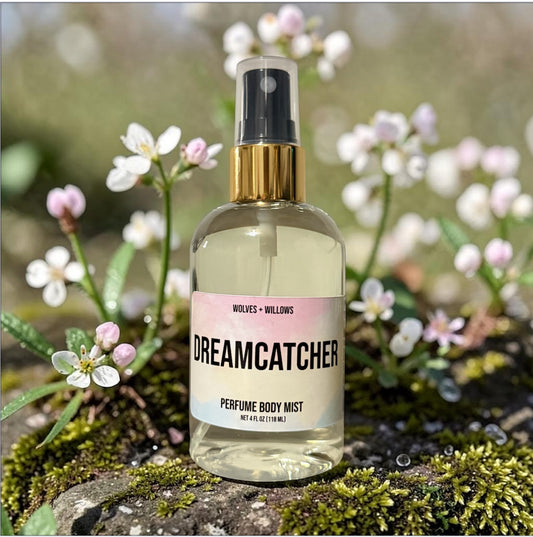 Perfume body mist bottle labeled 'Dreamcatcher' surrounded by flowers and greenery
