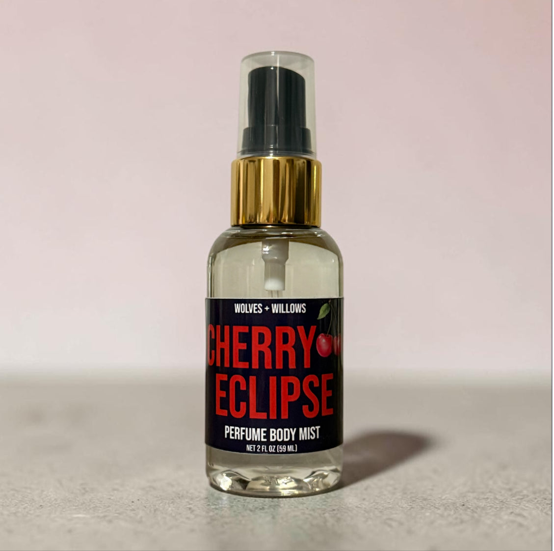 Perfume body mist bottle labeled 'Cherry Eclipse' by Wolves & Willows on a light pink background.