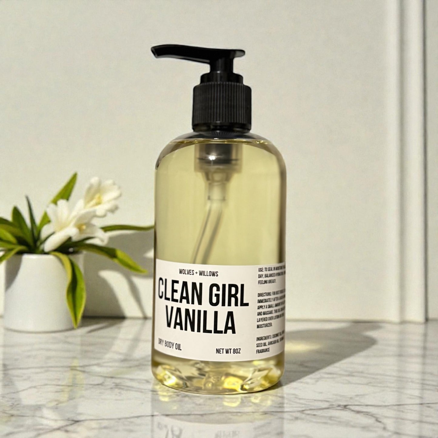 Bottle of 'Clean Girl Vanilla' body oil on a marble surface with a white background