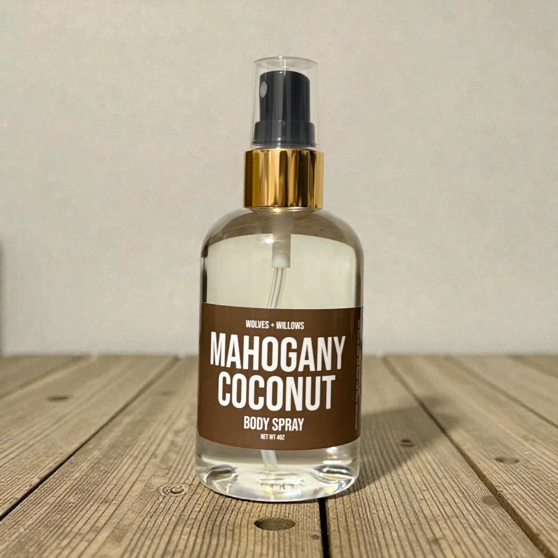 Body spray bottle labeled 'Mahogany Coconut' on a wooden surface with a neutral background