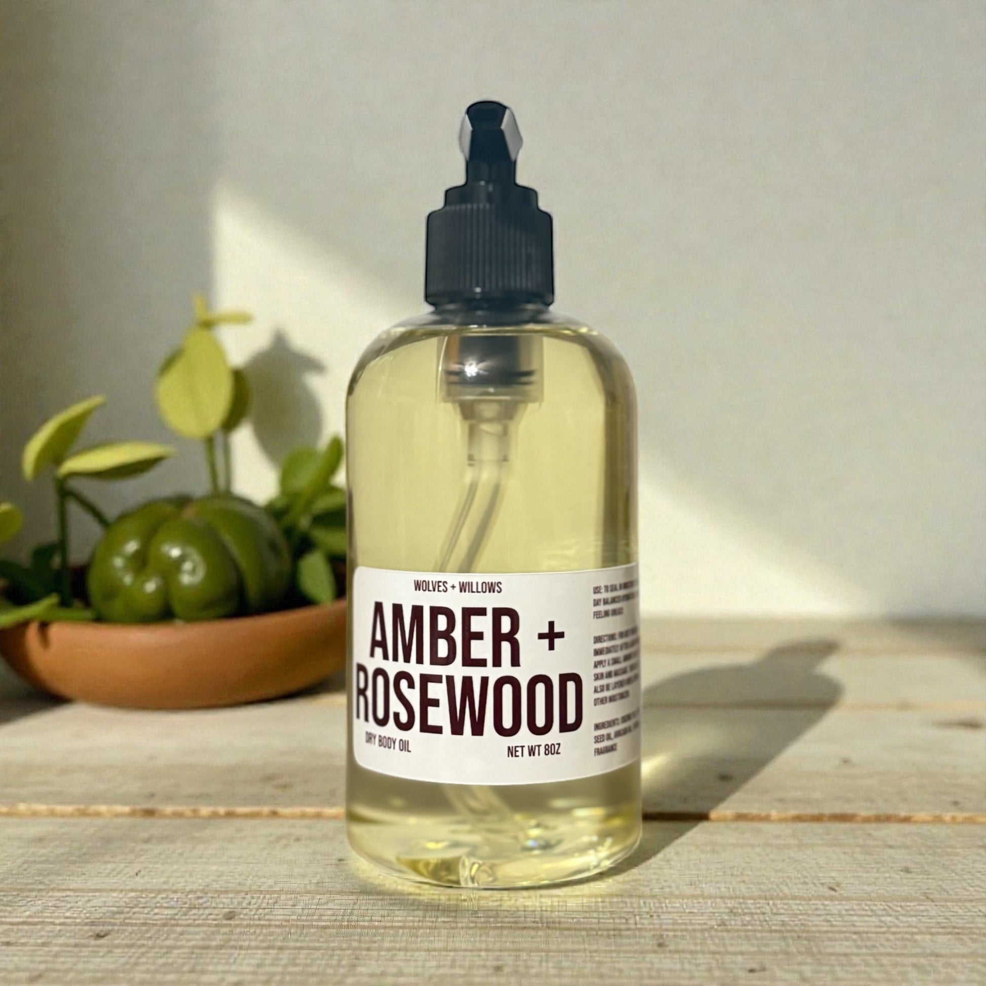 Amber and Rosewood 8 ounce body oil in clear bottle with black pump.
