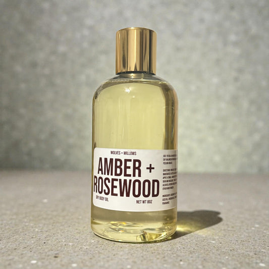 Amber and Rosewood 8 ounce body oil in clear bottle with gold dispensing cap.