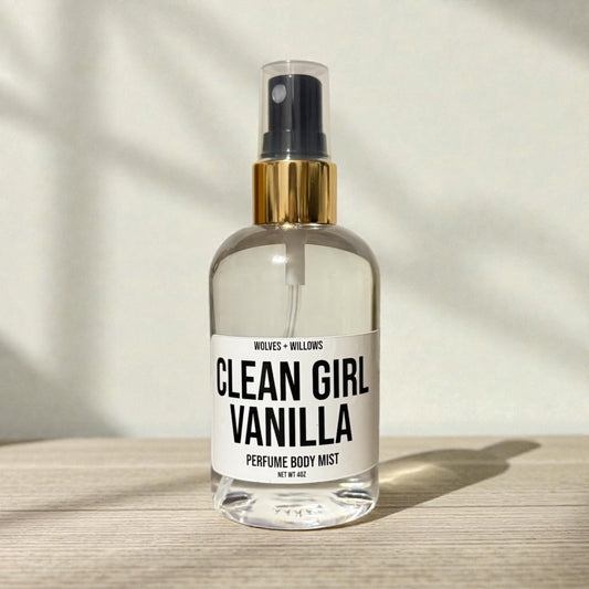 Clear spray bottle labeled 'Clean Girl Vanilla' on a wooden surface with a neutral background