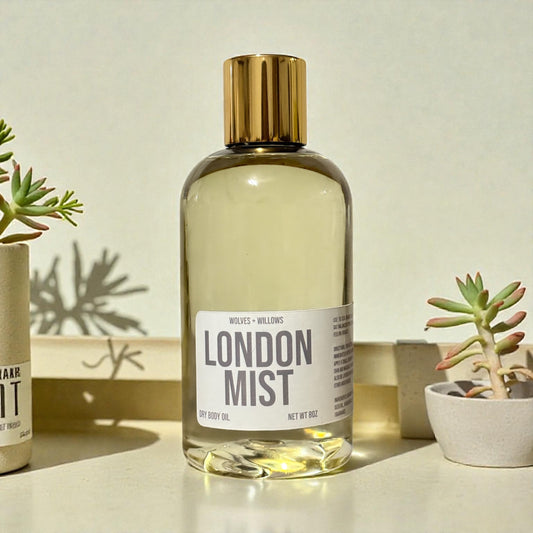 Bottle of 'London Mist' dry body oil with a gold cap on a neutral background