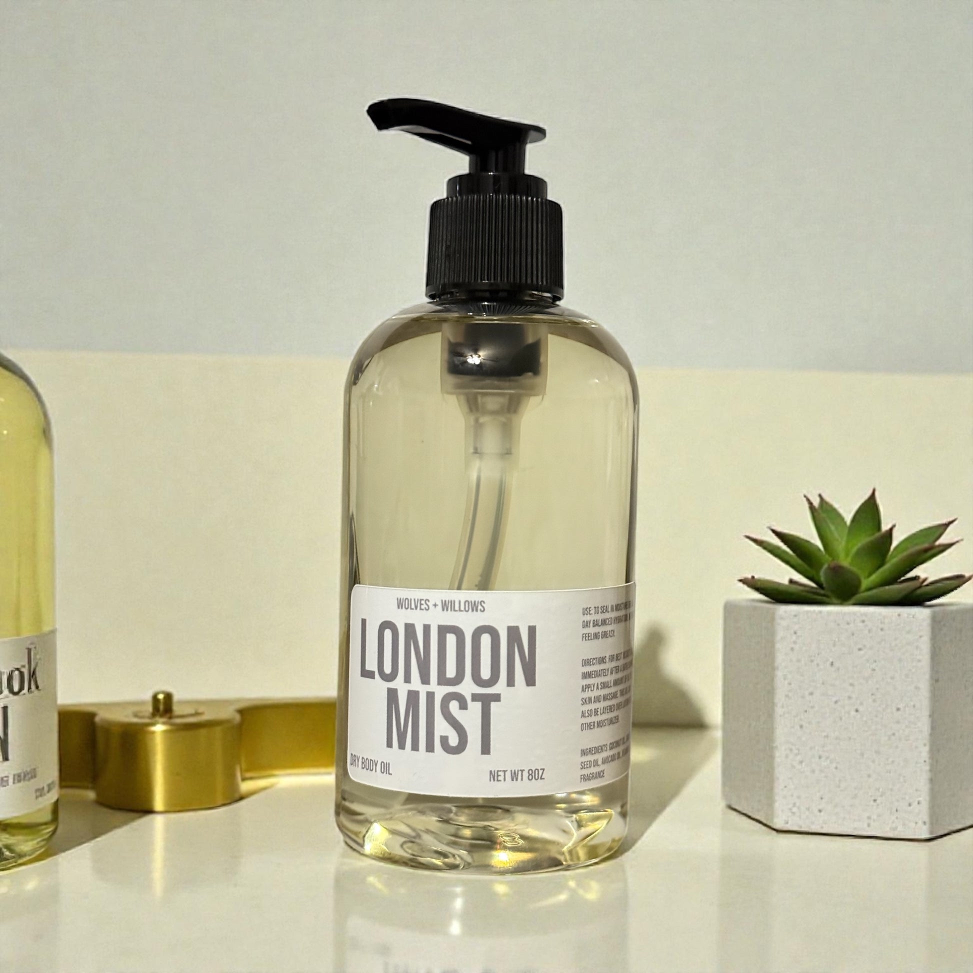 Bottle of 'London Mist' body oil on a neutral background with a plant and decorative items.