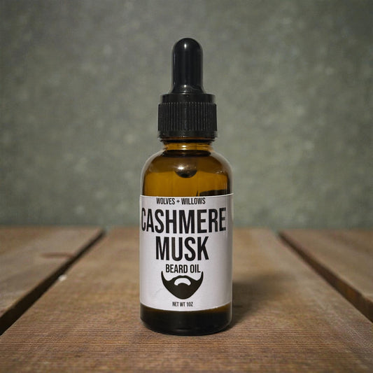 Bottle of Cashmere Musk beard oil with a dropper on a wooden surface and gray background