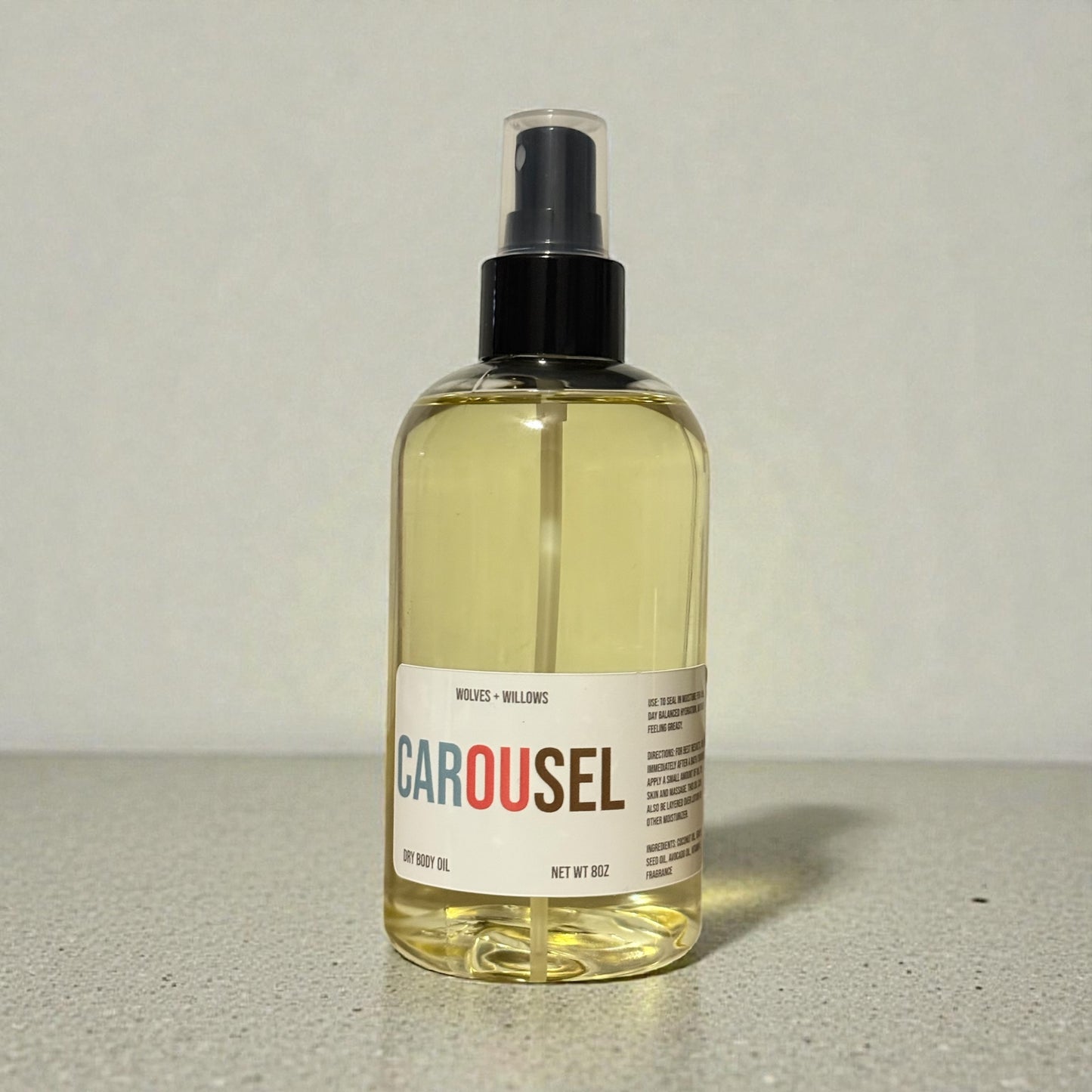 Bottle of 'Carousel' body oil on a neutral background