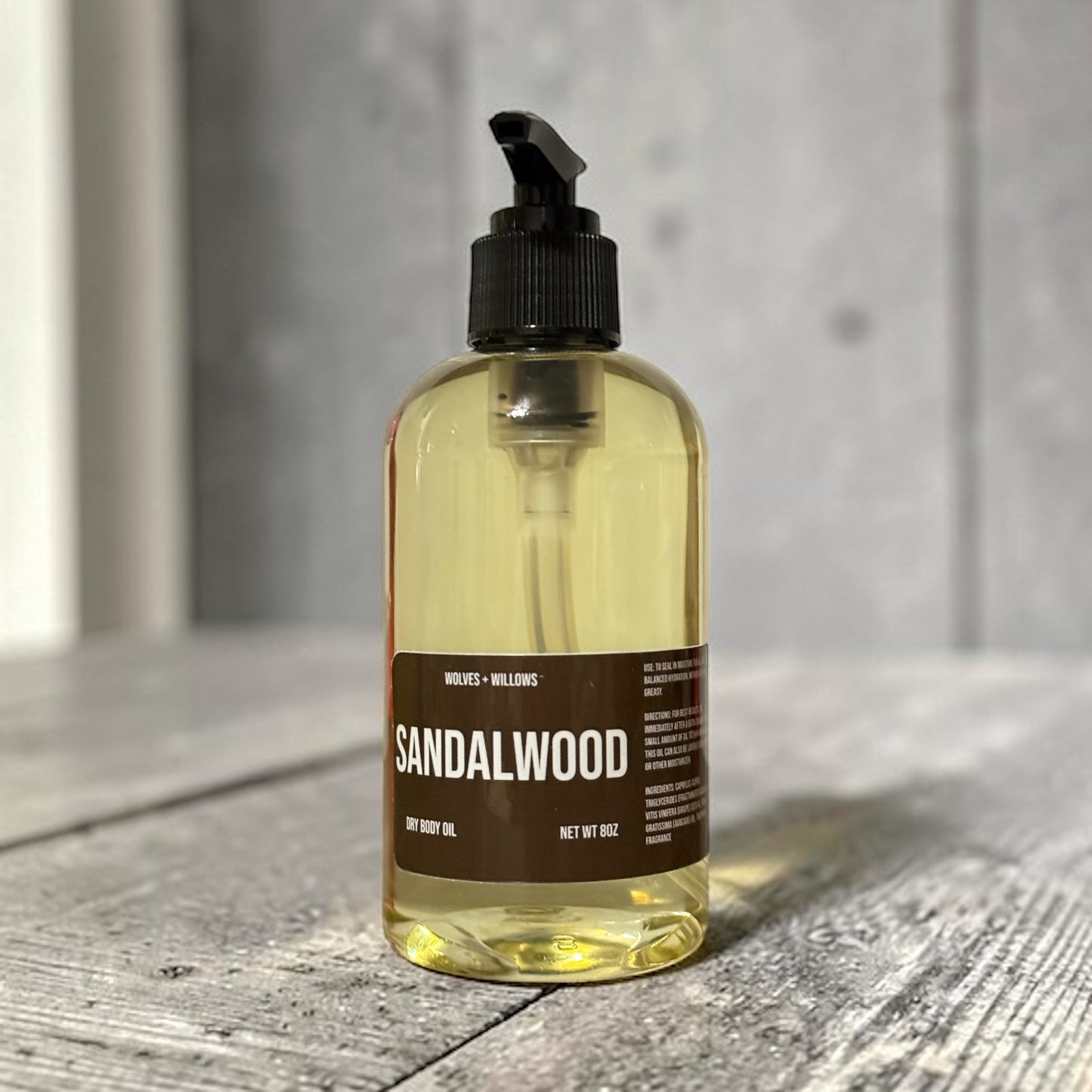 Bottle of sandalwood oil on a wooden surface with a neutral background