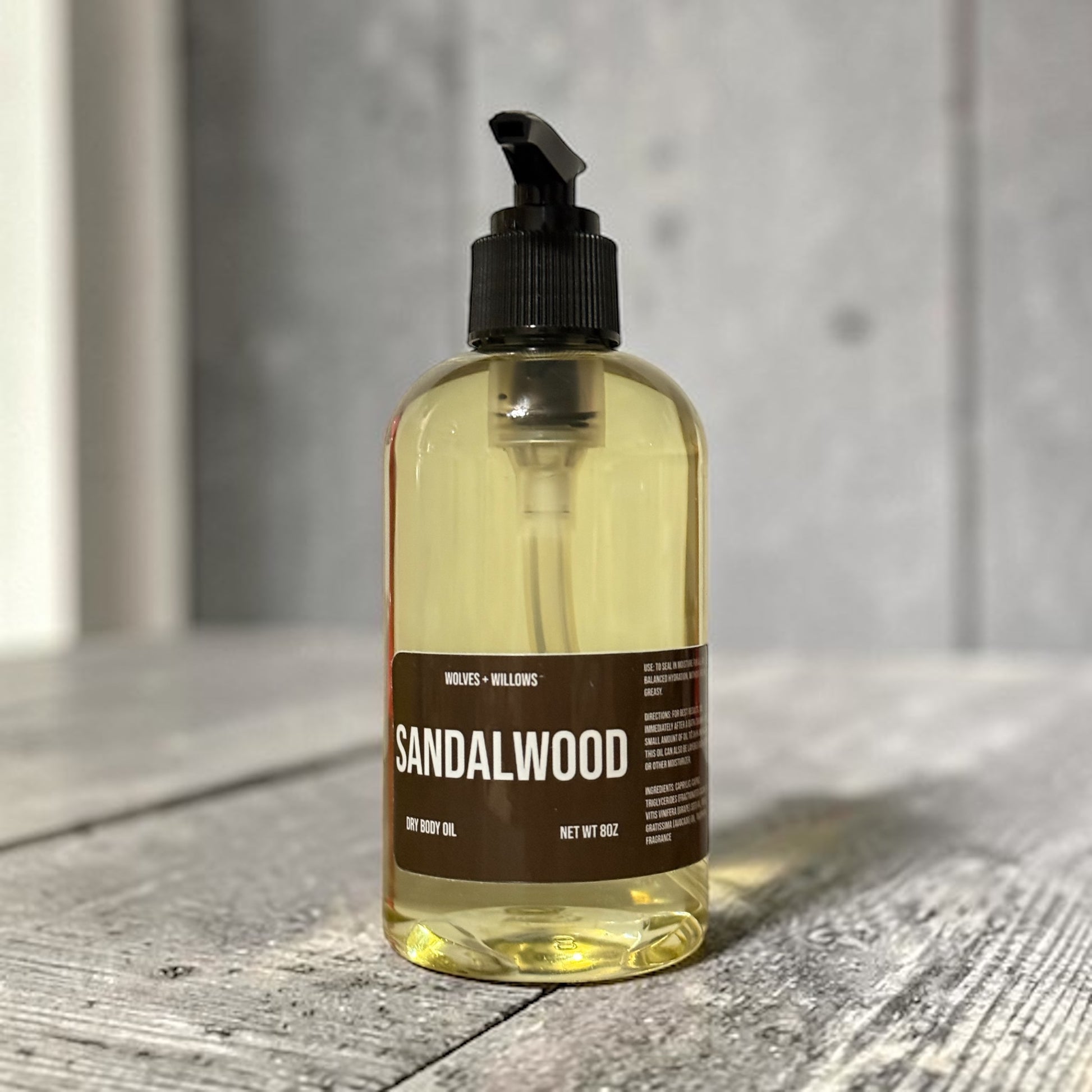 Bottle of sandalwood oil on a wooden surface with a neutral background