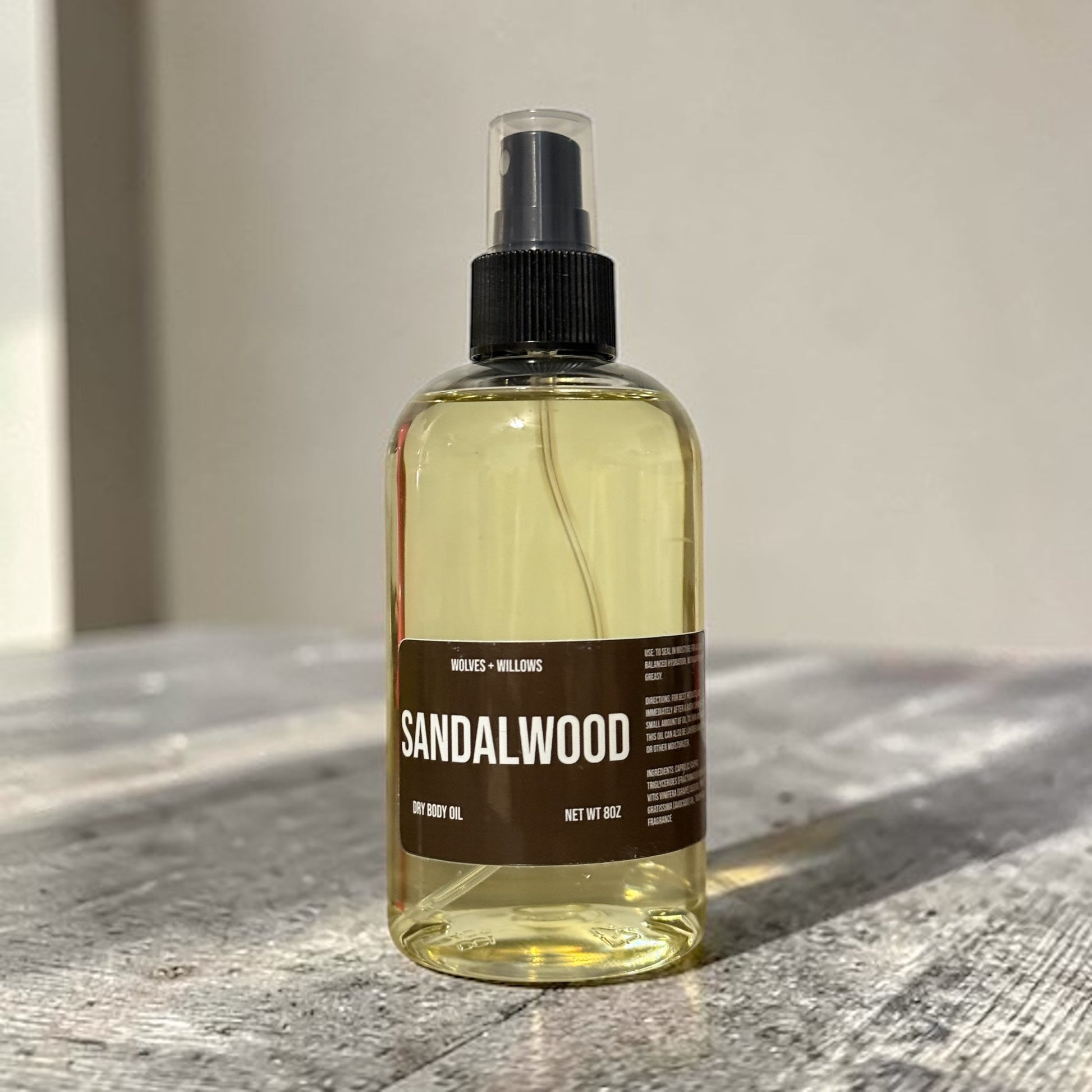 Bottle of sandalwood body oil on a wooden surface with a neutral background