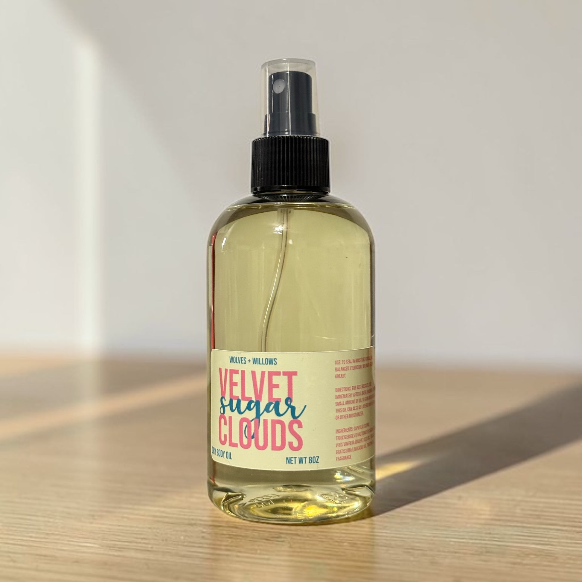 Bottle of 'Velvet Sugar Clouds' spray on a wooden surface with a light background