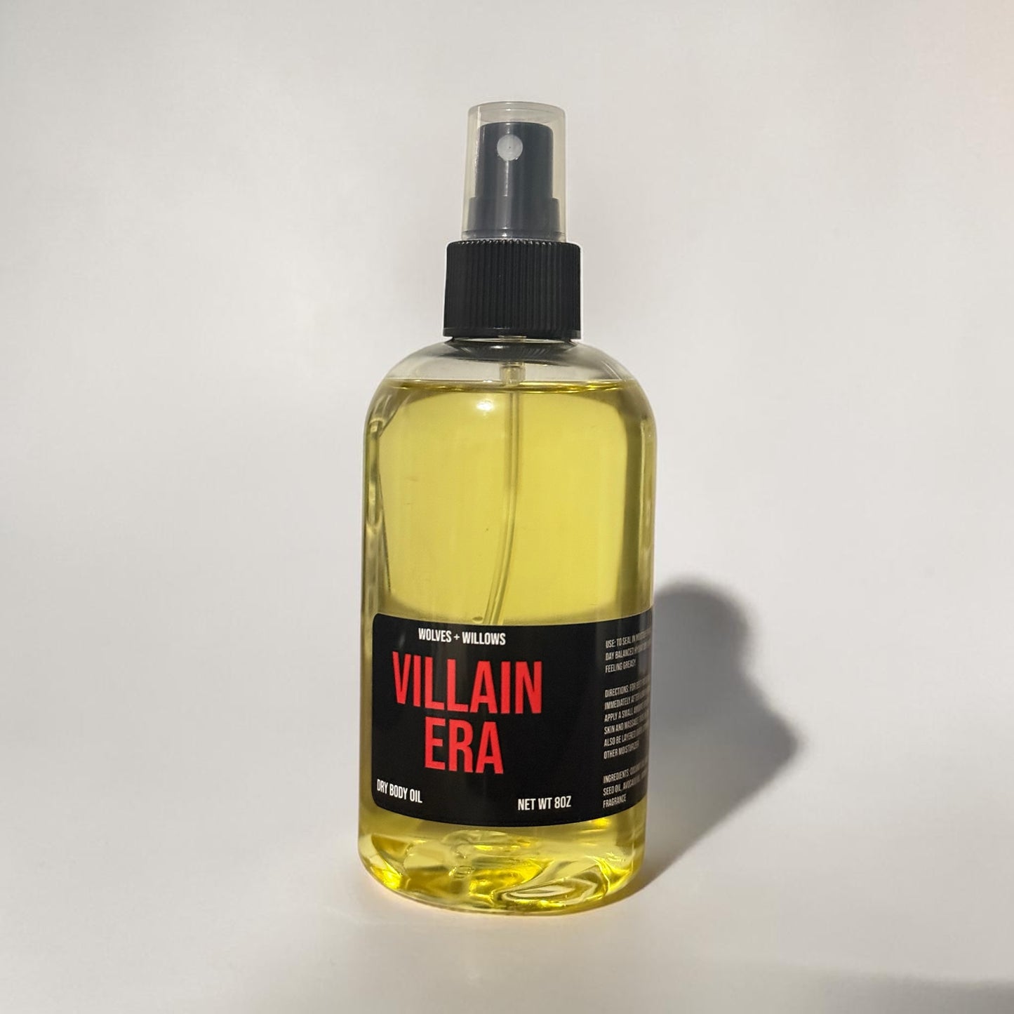 Bottle of Villain Era dry body oil with a black spray nozzle on a white background