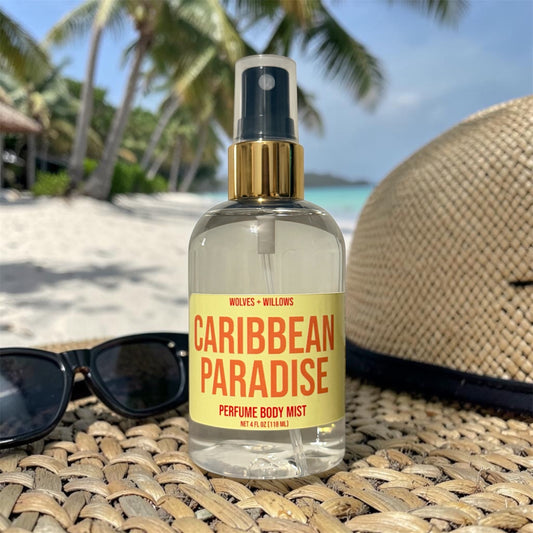 Bottle of 'Caribbean Paradise' perfume body mist with a straw hat and sunglasses on a beach setting.