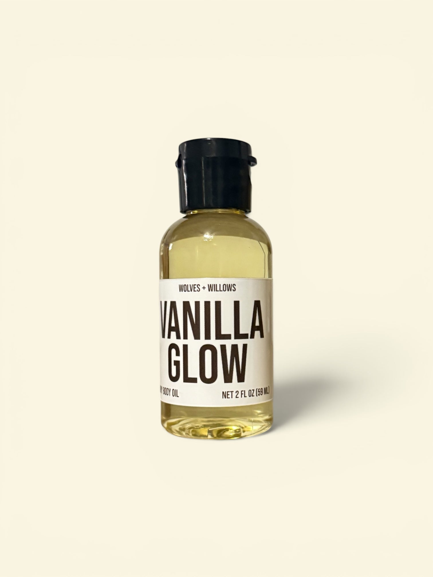 Bottle of Vanilla Glow body oil with a white label on a beige background