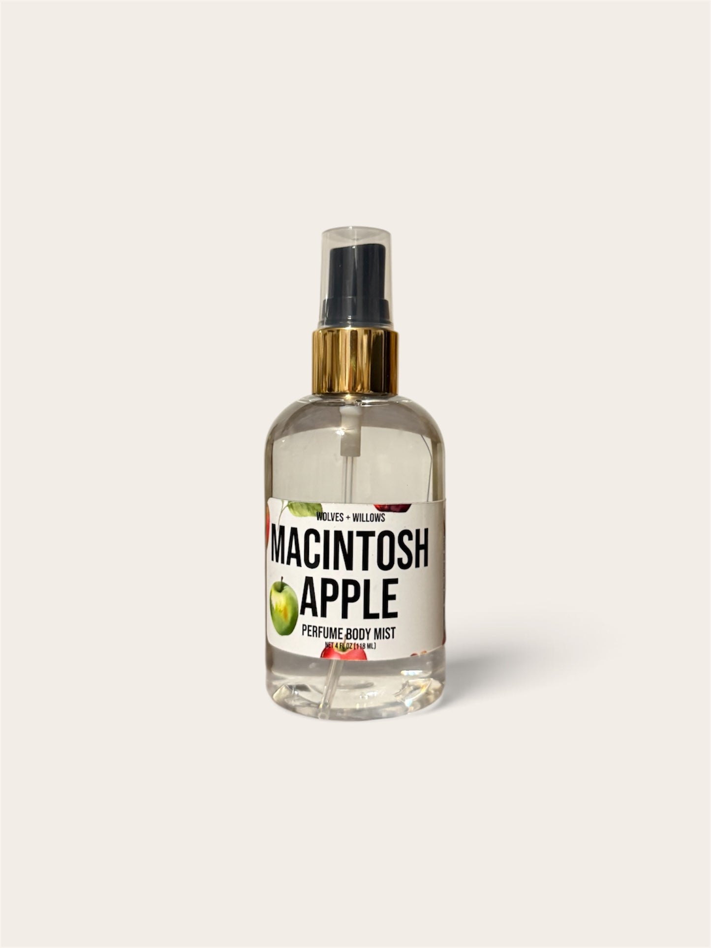 A clear glass perfume spray bottle labeled 'MACINTOSH APPLE' with a black spray top, gold collar, and green apple illustration, centered on a light warm gray background.