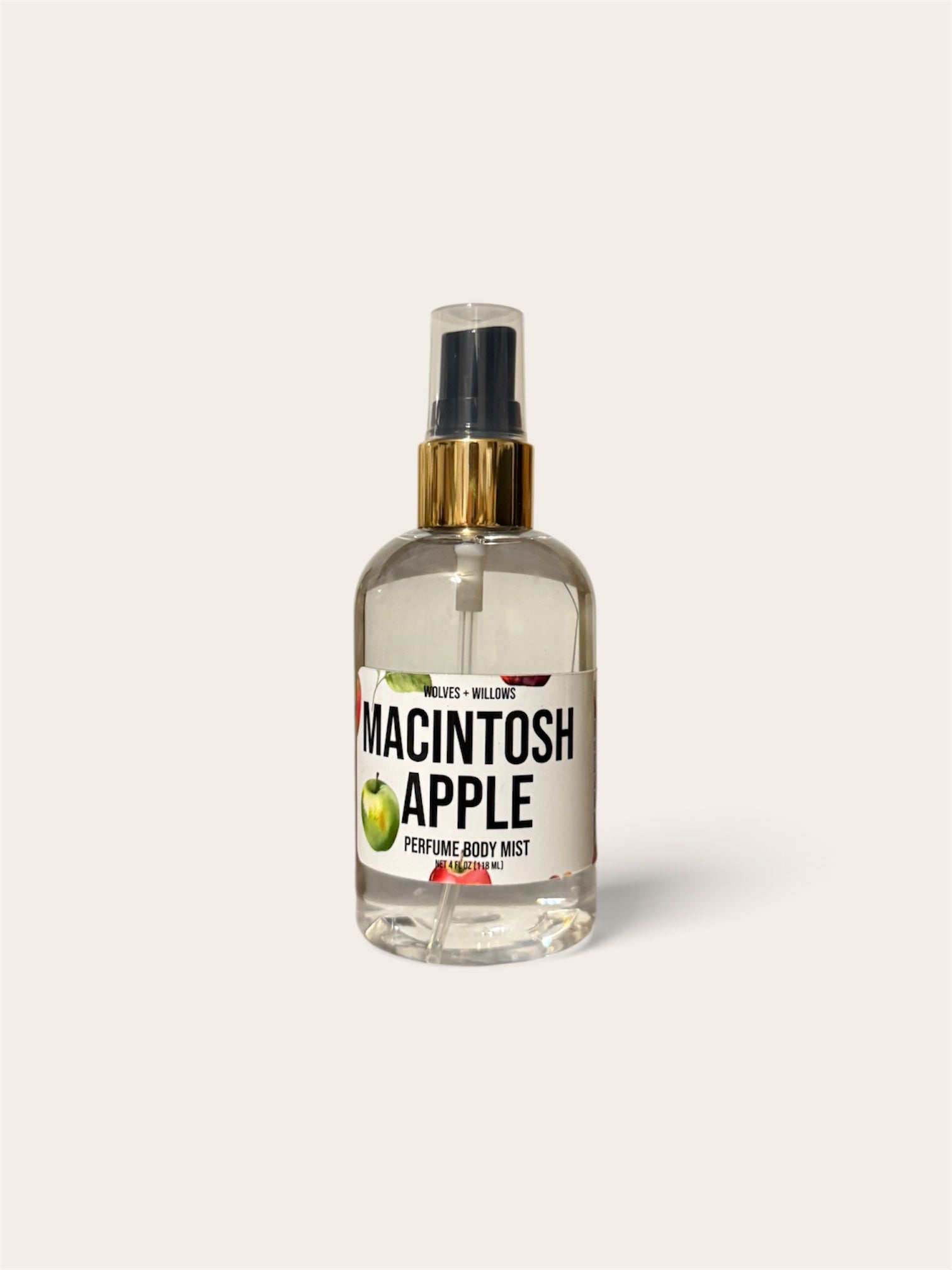 A clear glass perfume spray bottle labeled 'MACINTOSH APPLE' with a black spray top, gold collar, and green apple illustration, centered on a light warm gray background.