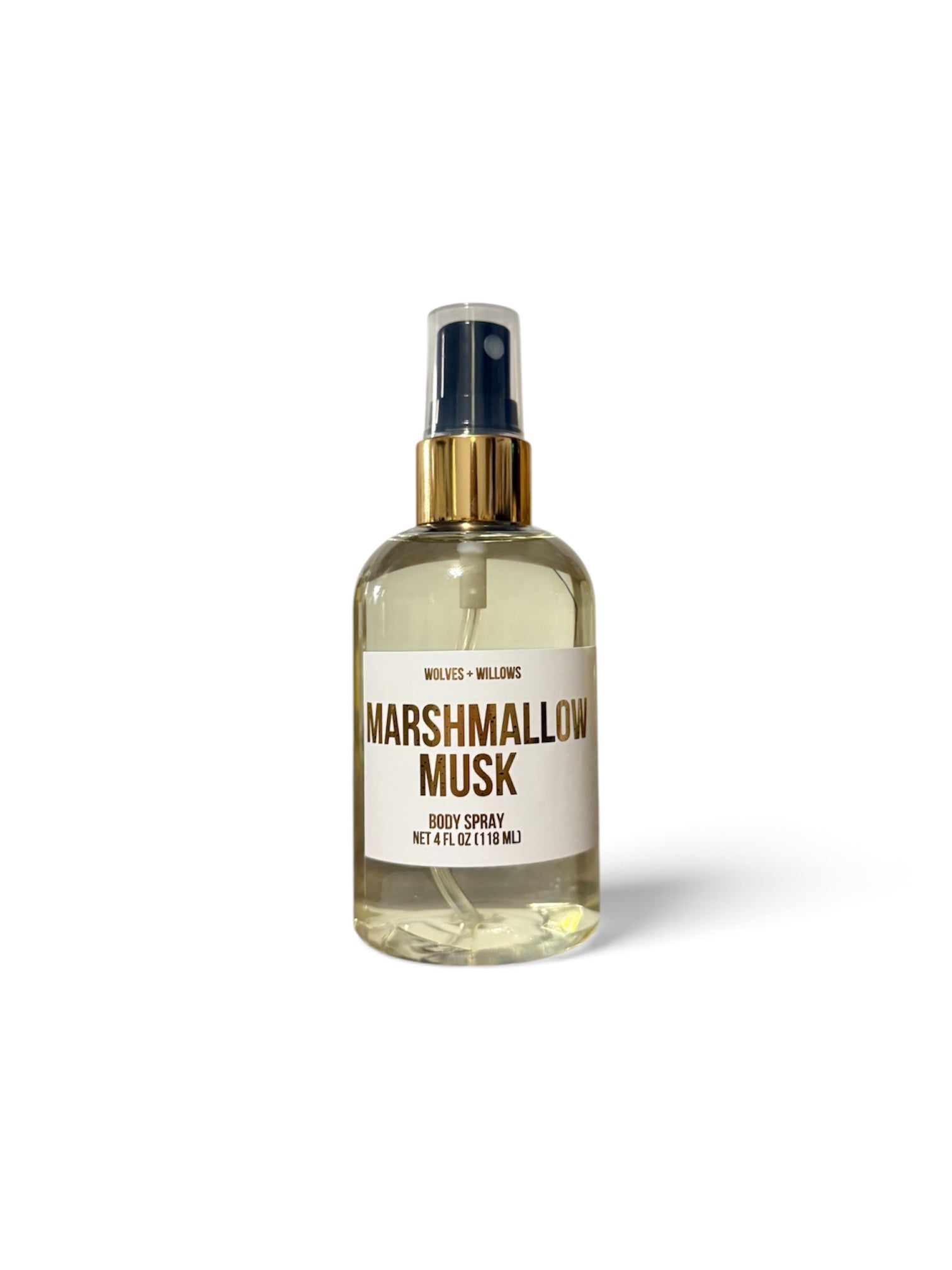 A clear glass body spray bottle filled with pale yellow liquid, featuring a cream label with brown text that reads 'MARSHMALLOW MUSK' and 'VELVET + WELLING'. The bottle has a gold-tone spray collar and a dark spray top, set against a clean white background with a soft shadow.