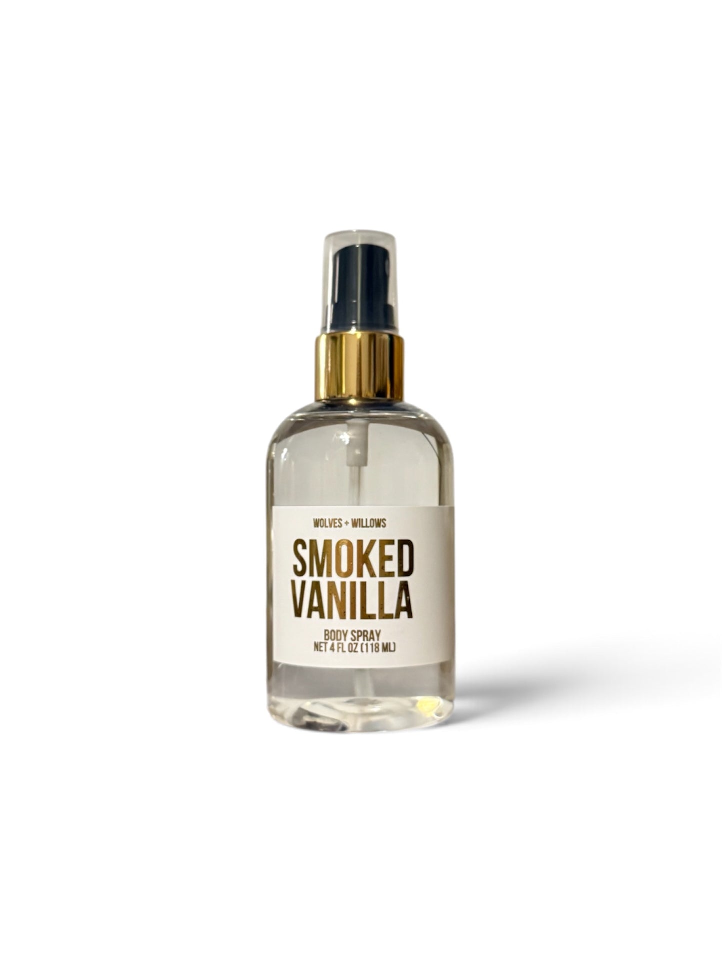 A clear glass body spray bottle with a gold spray collar and a cream label reading 'SMOKED VANILLA' on a white background.