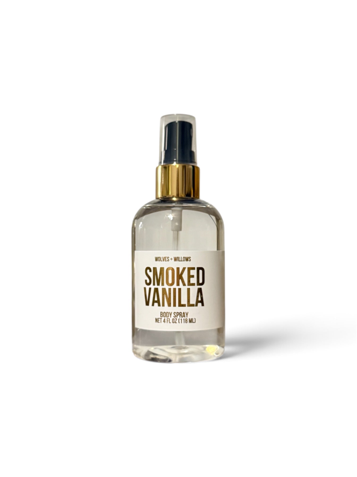 A clear glass body spray bottle with a gold spray collar and a cream label reading 'SMOKED VANILLA' on a white background.
