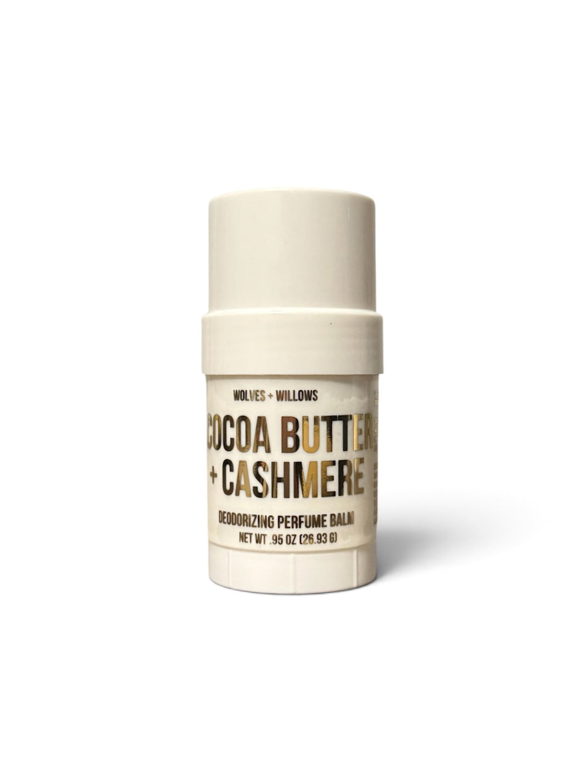 A single cylindrical perfume balm stick on a plain white background. The container is a warm cream color with a matching cap, featuring a label that reads 'COCOA BUTTER + CASHMERE' in dark brown and gold lettering.